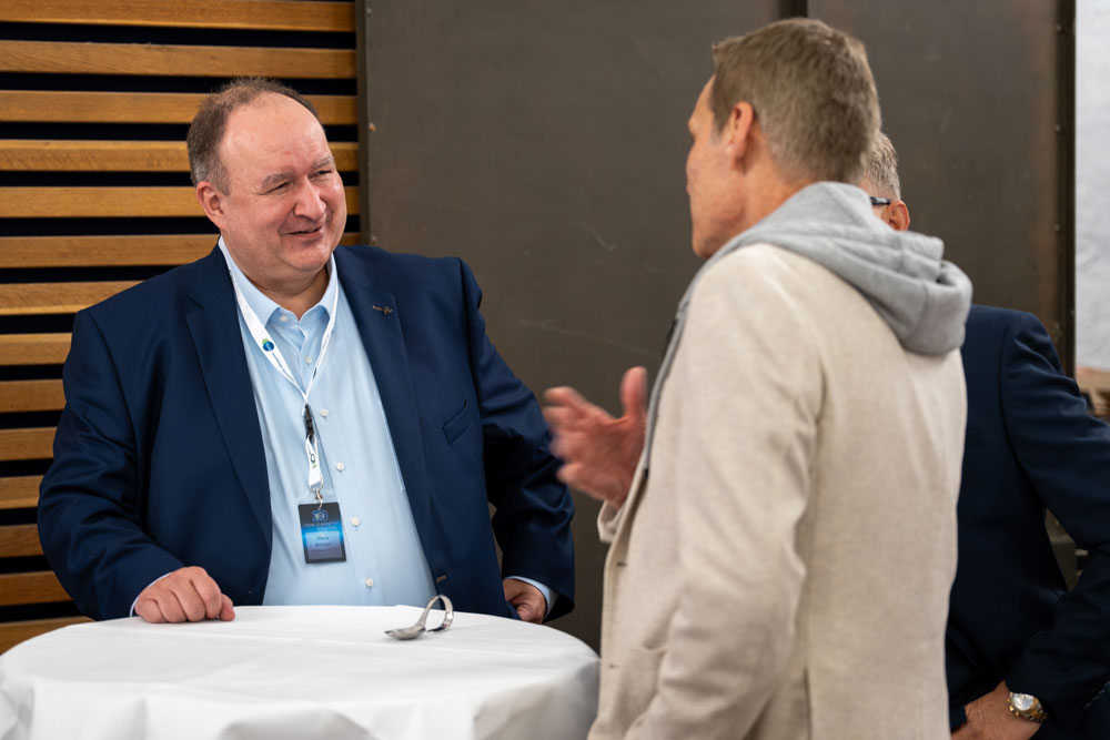 hsag-5 Zwei Männer im Gespräch an einem runden Tisch bei einer beruflichen Veranstaltung.